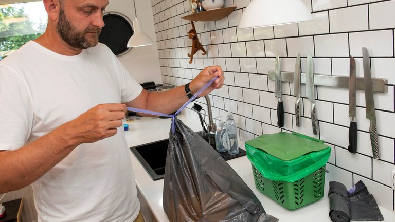 mand binder knude på affaldspose