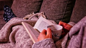 Bolig er kold, mand varmer sig med tæppe og kaffe