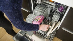 Kvindearm tager rent service fra nederste skuffe i opvaskemaskinen