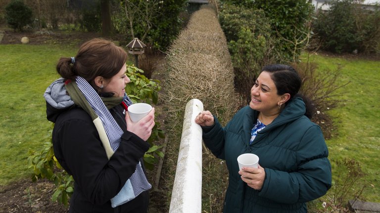 Naboer drikker kaffe henover hækken