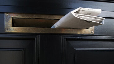 Brevsprække i dør med avis i