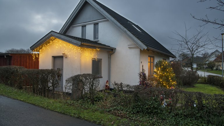 Hus med julekæde på gavl og i busk