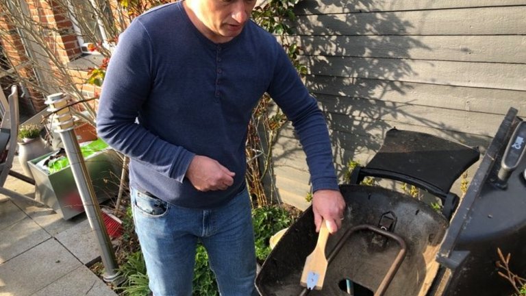 mand renser brænderrørerne på en Weber gasgrill