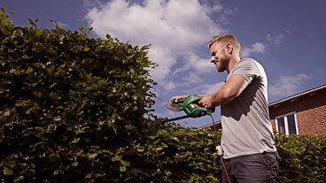 Mand klipper hæk ned til højde på 1 meter for at forebygge indbrud.
