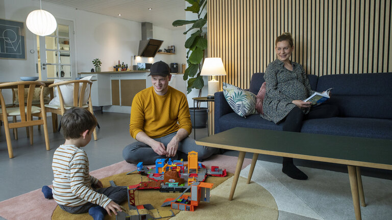 Far, mor og barn leger i stuen