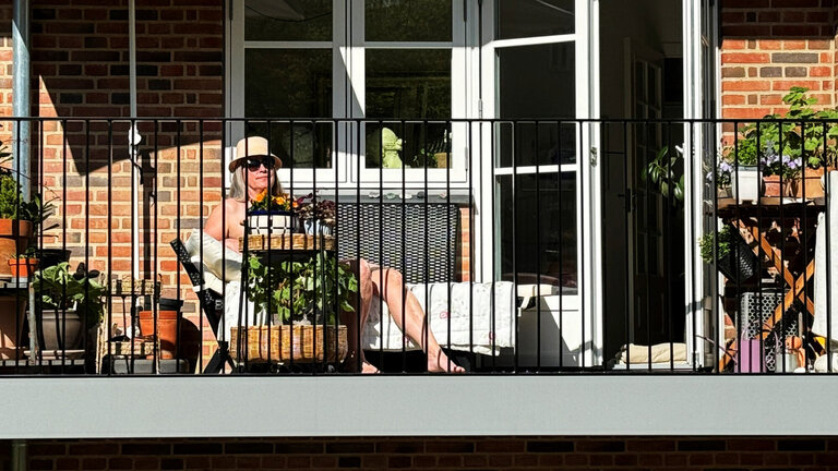 Kvinde solbader topløs og nøgen på altan