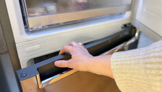 Hånd der åbner lågen på et køle/fryseskab