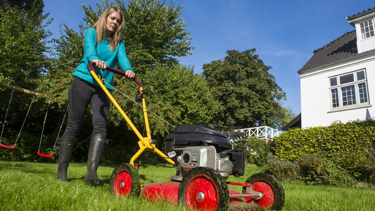 Kvinde slår græs med benzinplæneklipper