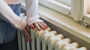Kvinde luner hænderne på radiatoren